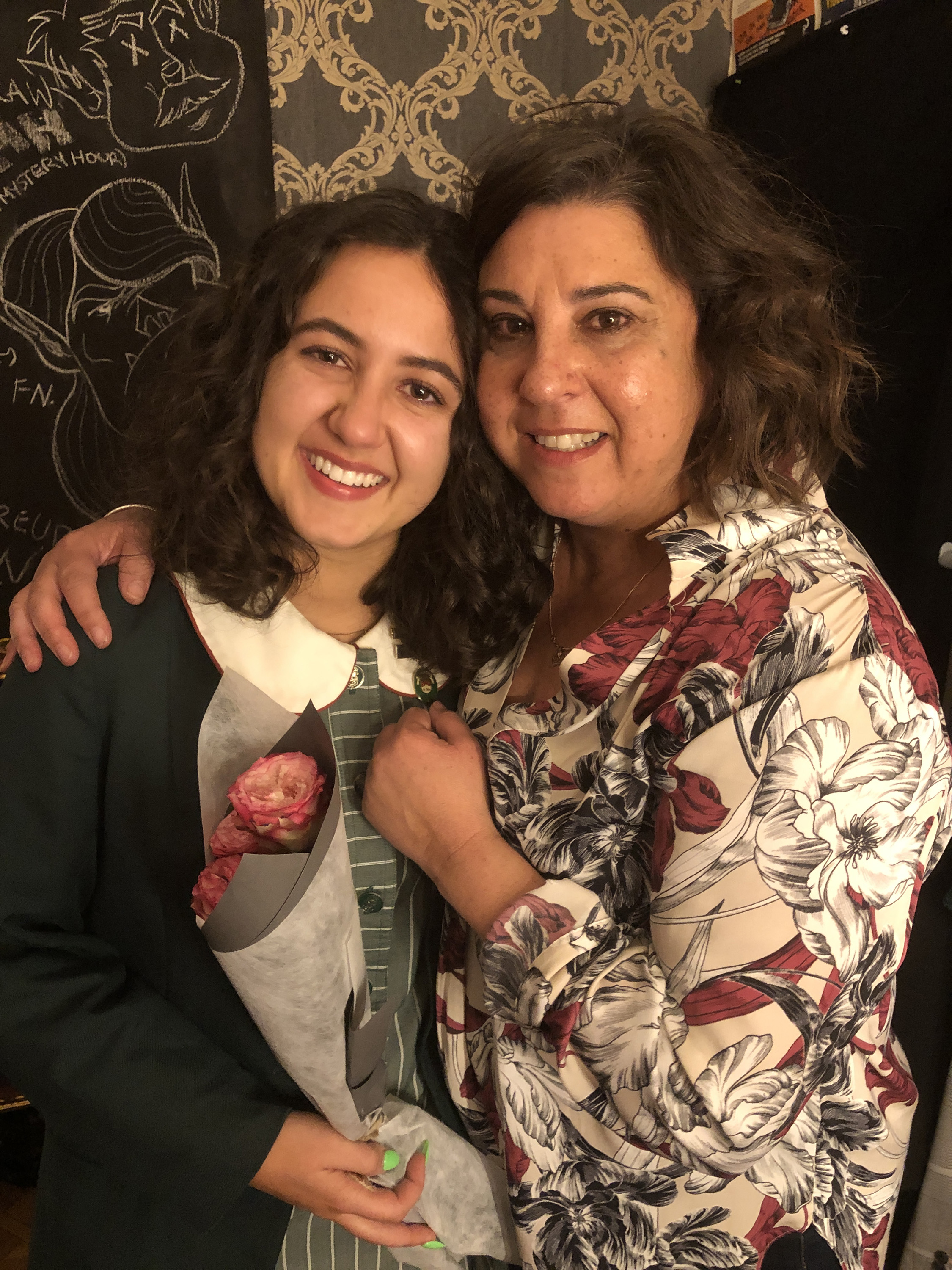 Two Italian Australian women, one in her 20s, the other in her 50s, smile into the camera. They are hugging, teary-eyed.