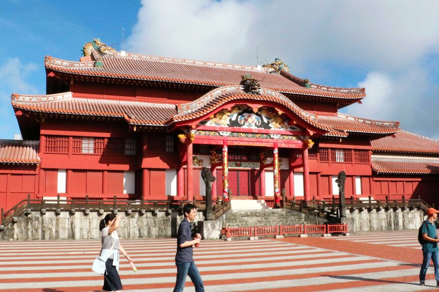 The bright red Shuri temple with a blue sky behind it