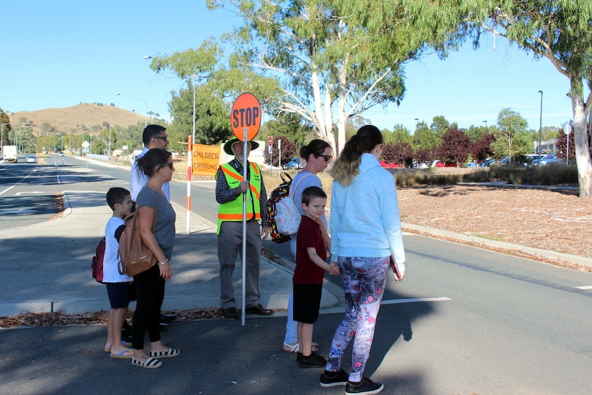 Families cross over a road crossing outside a school.