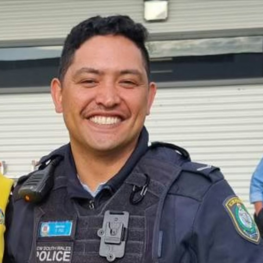 A man in a police uniform smiles at the camera.