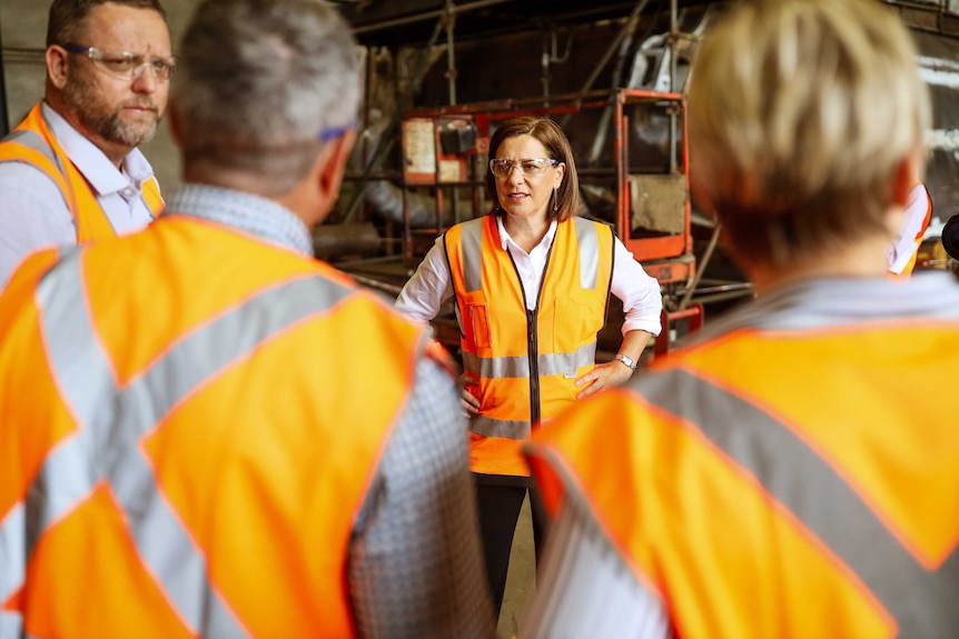 Deb Frecklington stands in a factory wearing a high vis vest on election campaign trial in Mackay.
