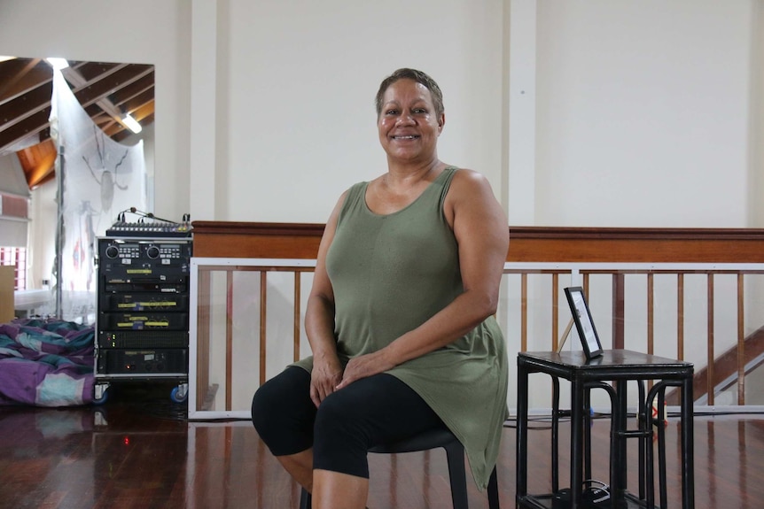 Middle aged Aboriginal woman sitting in a chair surrounded by theatre equipment