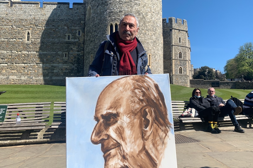 Seorang pria berdiri di luar Kastil Windsor dengan lukisan Pangeran Philip