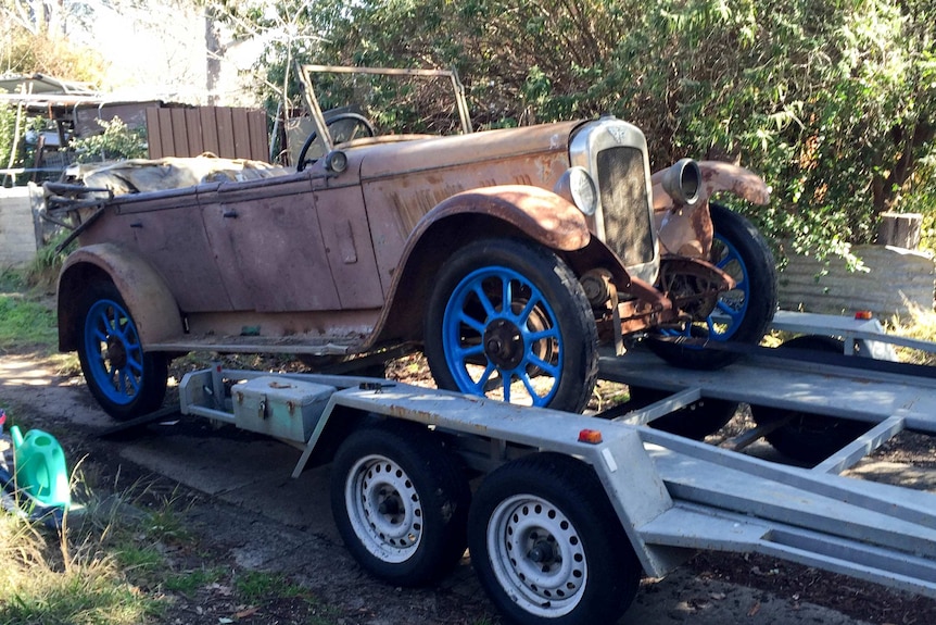 A rusty 1927 Austin Tourer is lifted onto a trailer