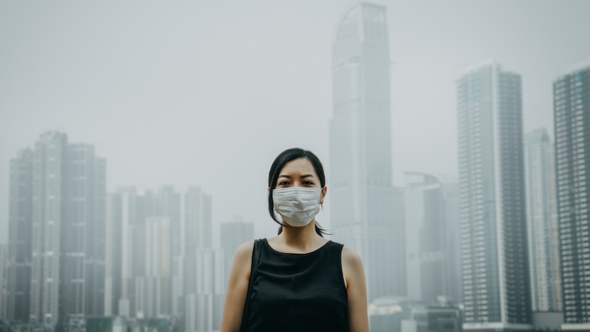 Young woman wearing protective face mask in city due to the polluted air