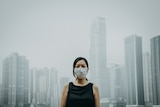 Young woman wearing protective face mask in city due to the polluted air