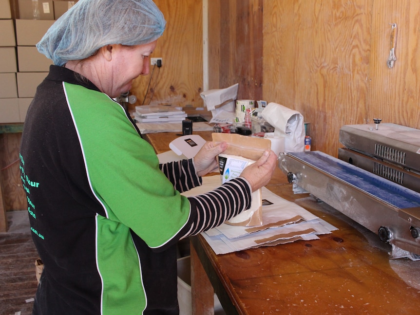 Side-on view of a woman sealing a package of flour from the ancient wheat variety 