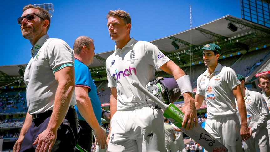 England cricketer Jos Buttler walks carrying a cricket bat 