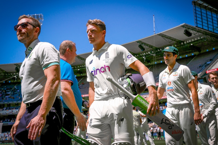 England cricketer Jos Buttler walks carrying a cricket bat 