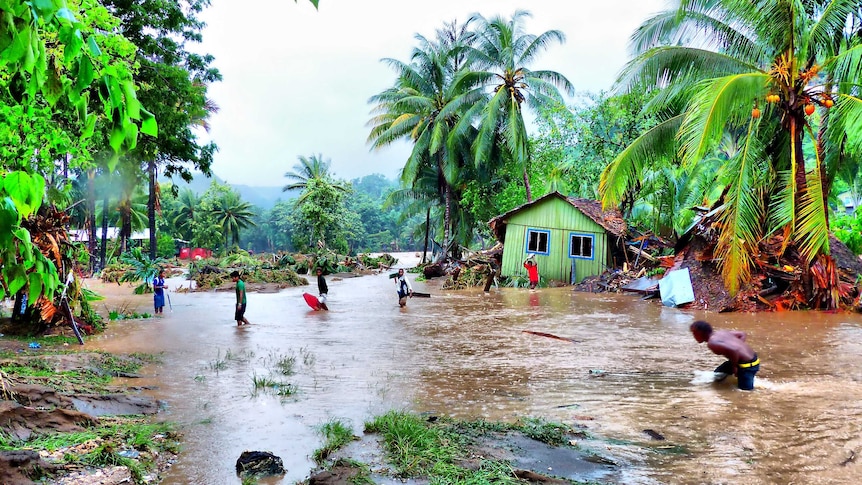 Locals walk through floodwaters after days of heavy rain in the Solomon Islands.