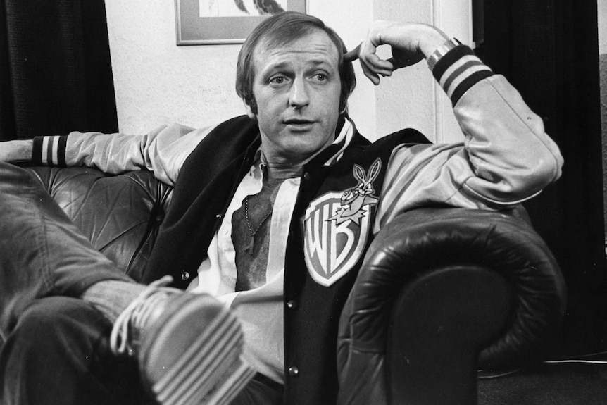 British actor Graham Chapman sits in a leather armchair.