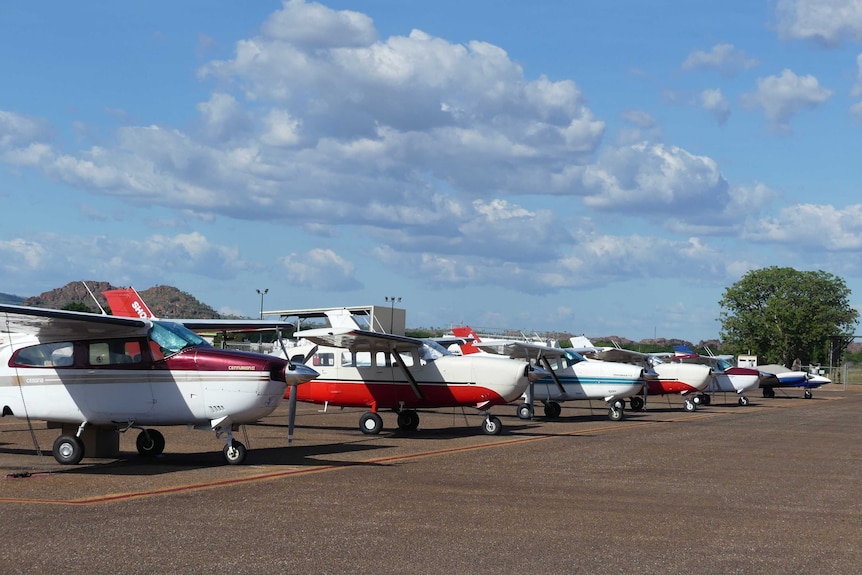 Six small charter aircraft lined up on airport tarmac