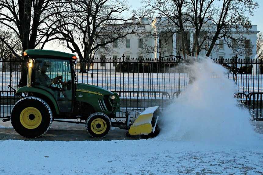 Workers plough snow in front of the White House