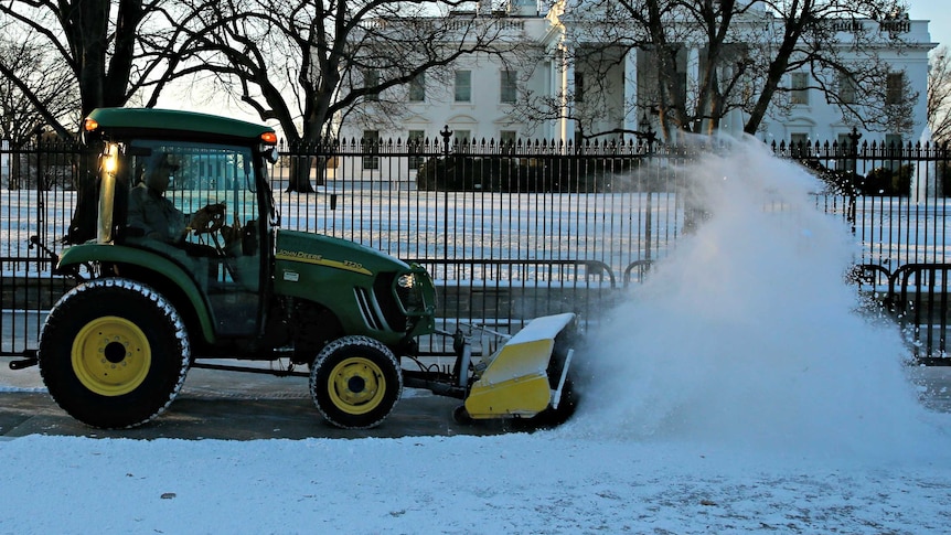 Workers plough snow in front of the White House