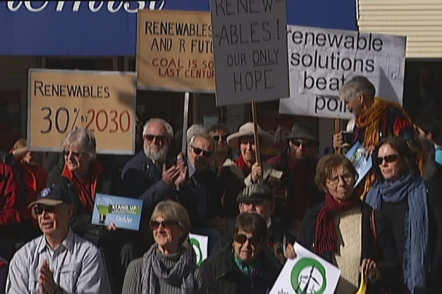 Protesters hold up signs at a Canberra rally supporting renewable energy sources such as wind farms.