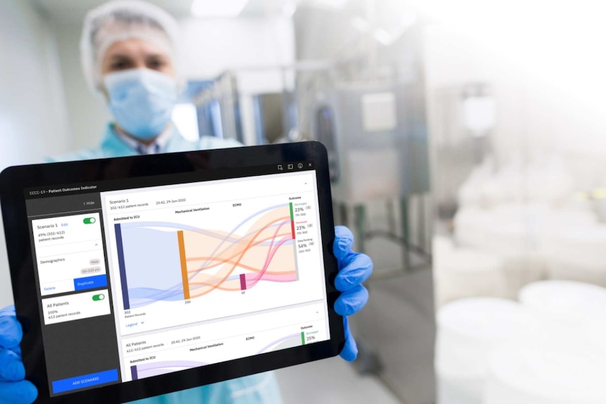 A health care worker wearing a mask holds up a computer with the app.