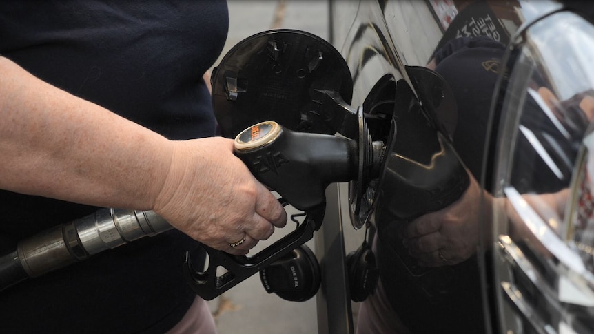 close up of persons hand pumping fuel into car
