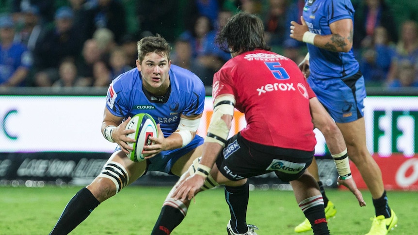 Western Force forward Richard Hardwick carries the ball wearing a blue jersey towards an opponent in red.
