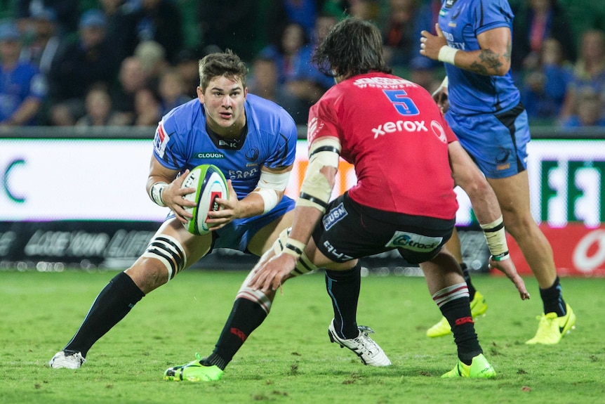 Western Force forward Richard Hardwick carries the ball wearing a blue jersey towards an opponent in red.