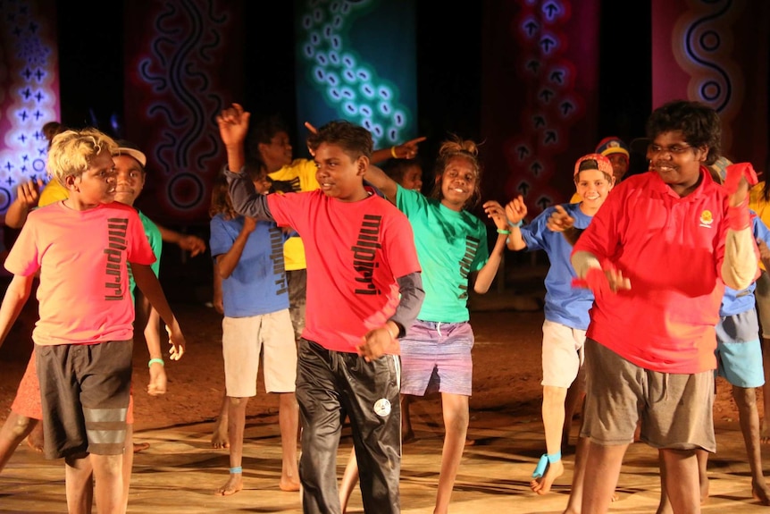 A group of youth dressed in colourful shirts take part in Warlpiri desert dance in Central Australia. October 15, 2016.