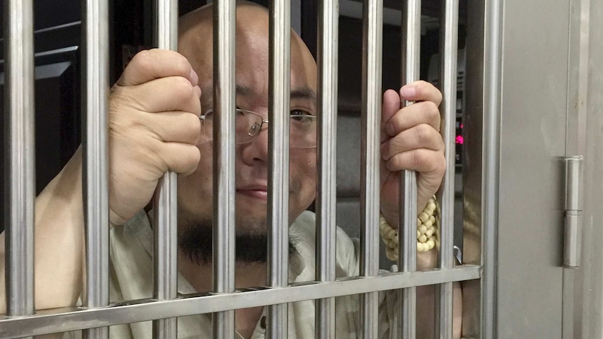 Wu Gan is seen behind bars at a police station.