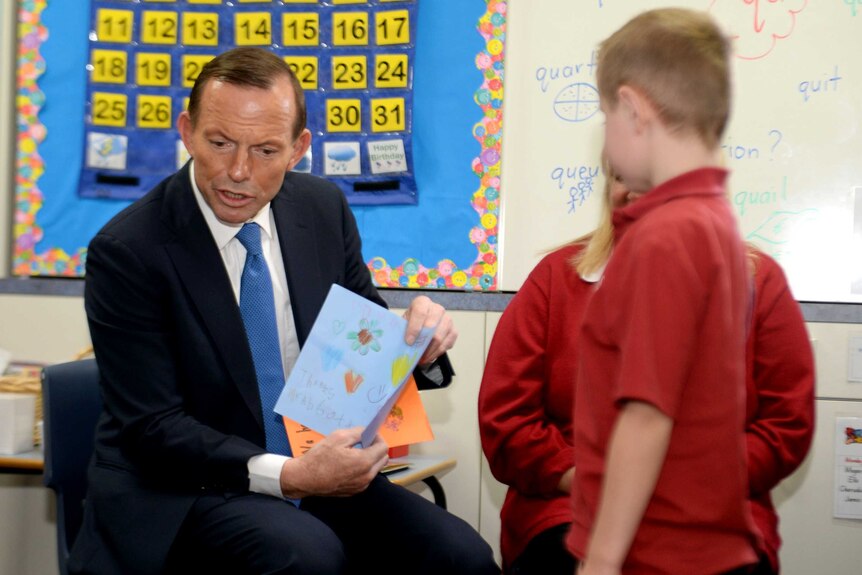 Opposition Leader Tony Abbott displays a card given to him from a class at Penrith Christian School.