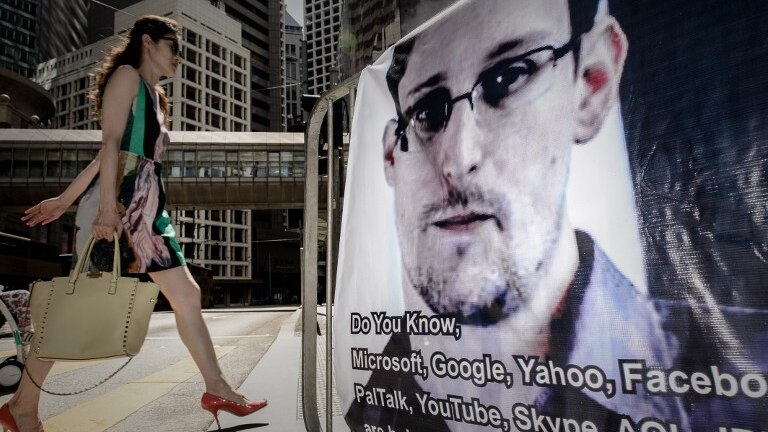 A woman walks past a banner displayed in support of Edward Snowden in Hong Kong