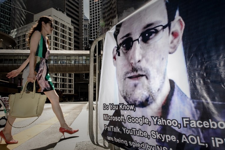 A woman walks past a banner displayed in support of Edward Snowden in Hong Kong