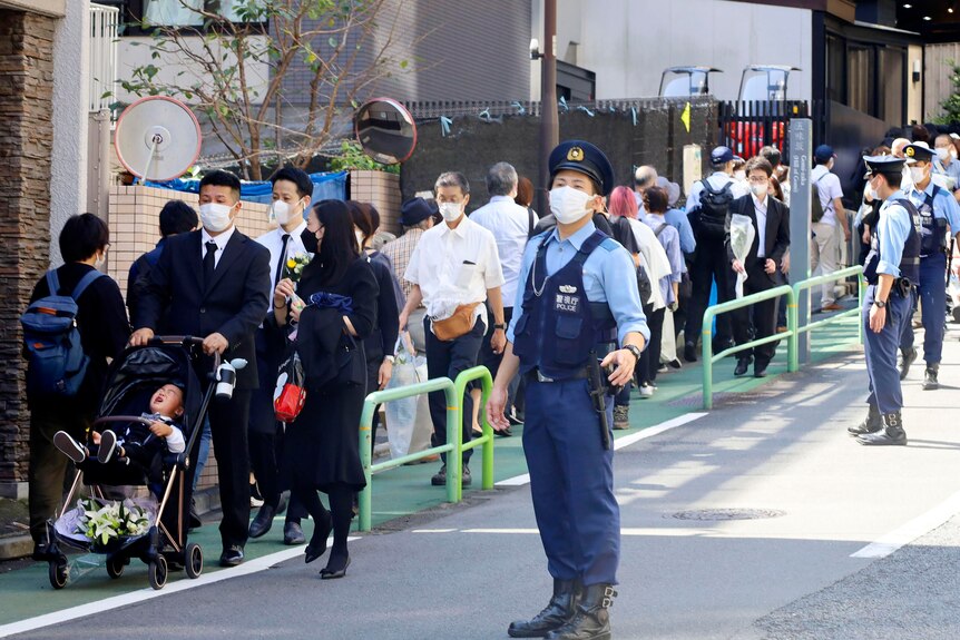 People make a long line to lay flowers and pay respects to former Japanese Prime Minister Shinzo Abe.
