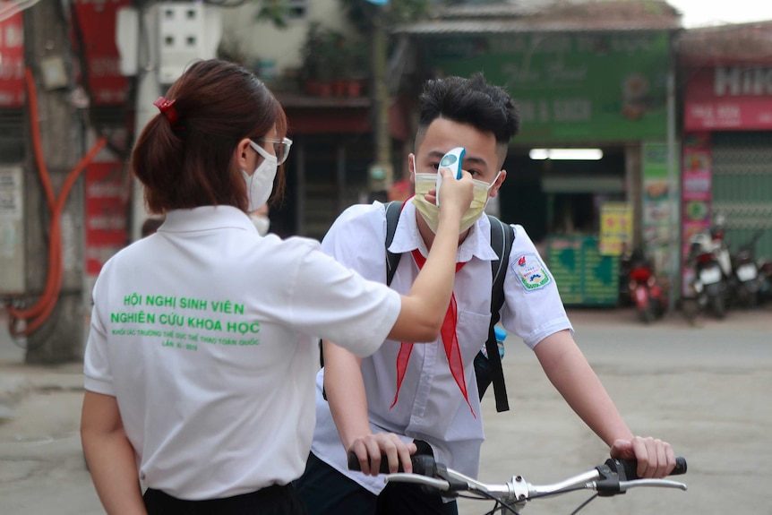 A student is scanned for temperature before entering Dinh Cong secondary school in Hanoi.