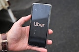 mans hand holding phone with the Uber logo open on it