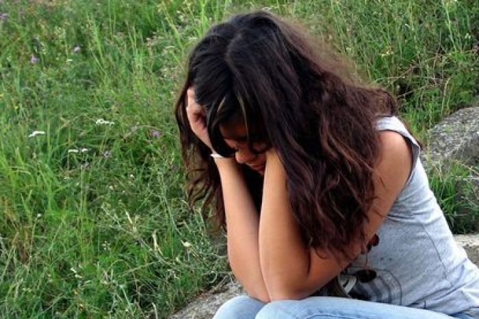 A depressed young woman sits on steps.