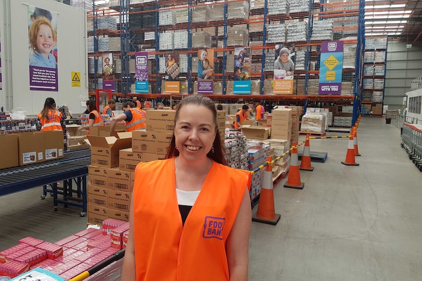 Brianna Casey standing in warehouse with volunteers unpacking boxes