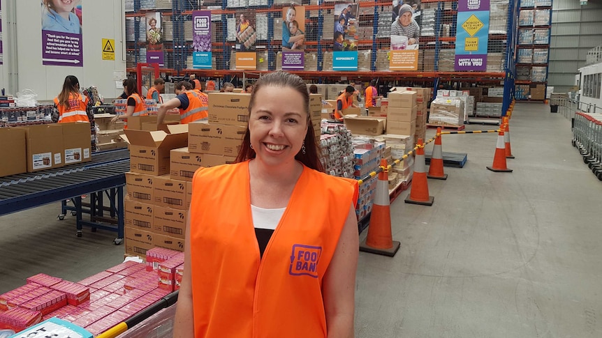 Brianna Casey standing in warehouse with volunteers unpacking boxes