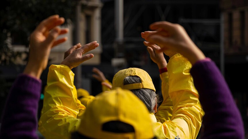 Falun Gong practitioners lift their hands.