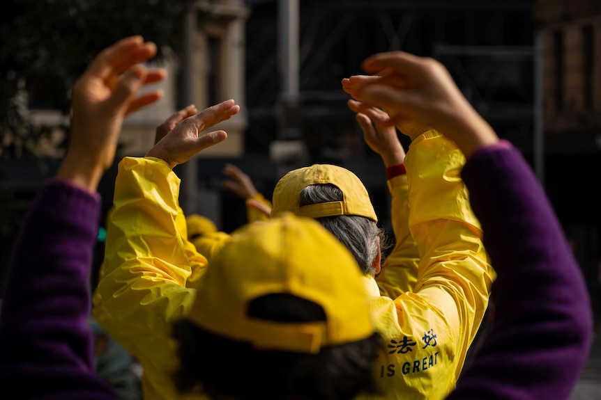 Falun Gong practitioners lift their hands.