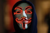 An Anonymous supporter wears a Guy Fawkes mask