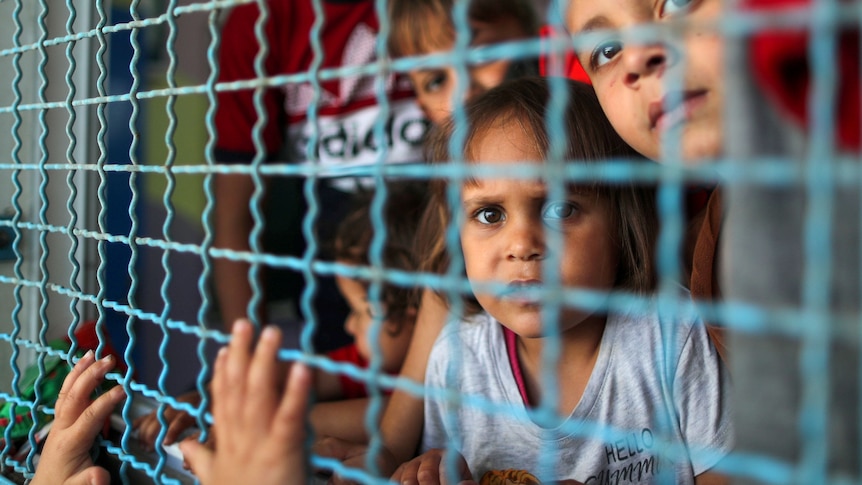 Palestinian children look through a window fence at a United Nations-run school where they take refuge, in Gaza Cityo