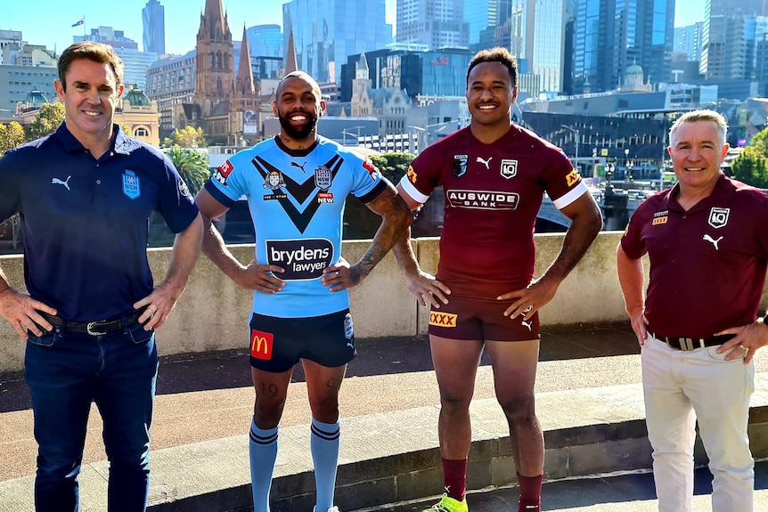 Four man stand and smile with their hands on their hips