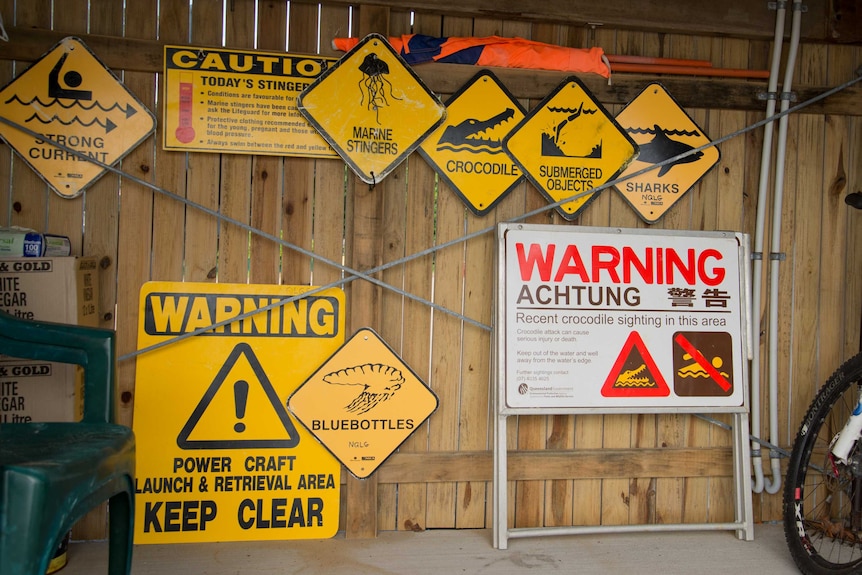 Signs used on far north Queensland beaches include 'recent crocodile sighting' warnings and 'marine stinger' warnings.