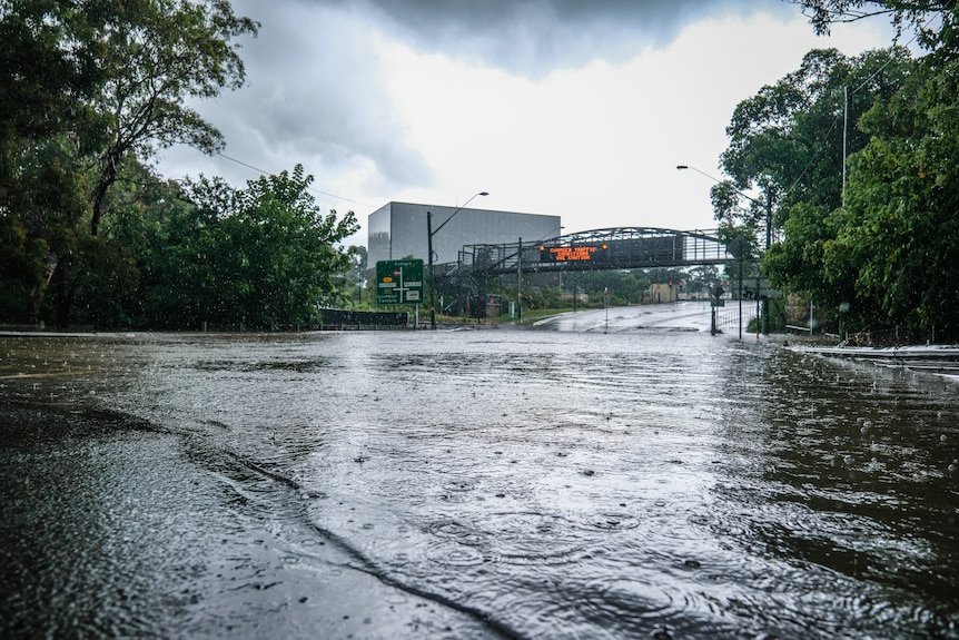 flooded road leading under a steel arch bridge