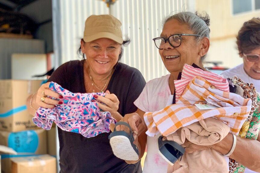 Two women fold donated clothes at a warehouse in Broome, January 2023.