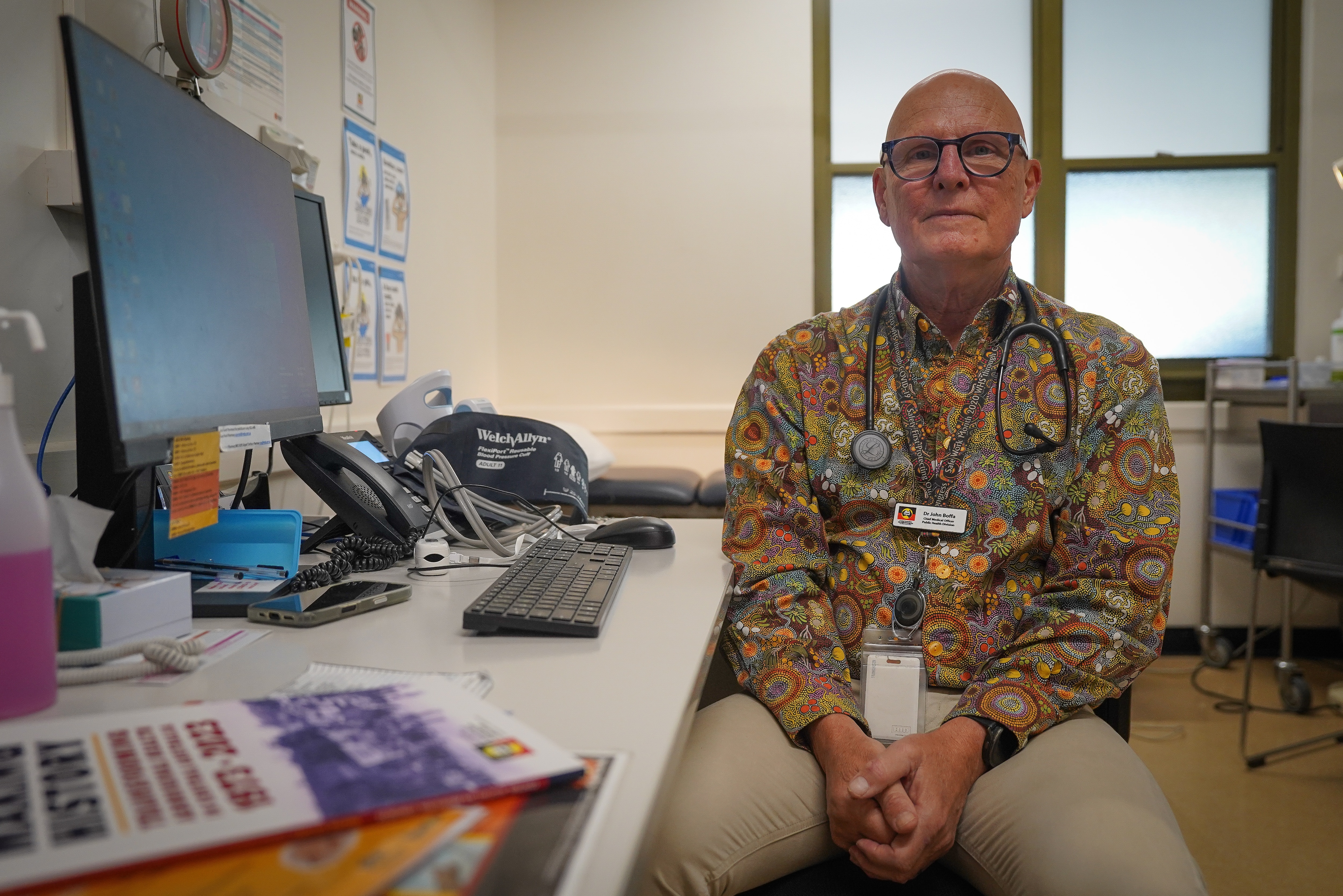 A doctor sitting in his office with a stethoscope around his neck.