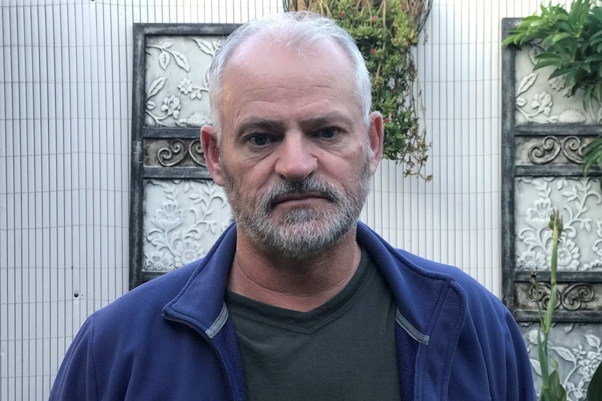 Steven Hession looks into the camera with a garden wall behind him.