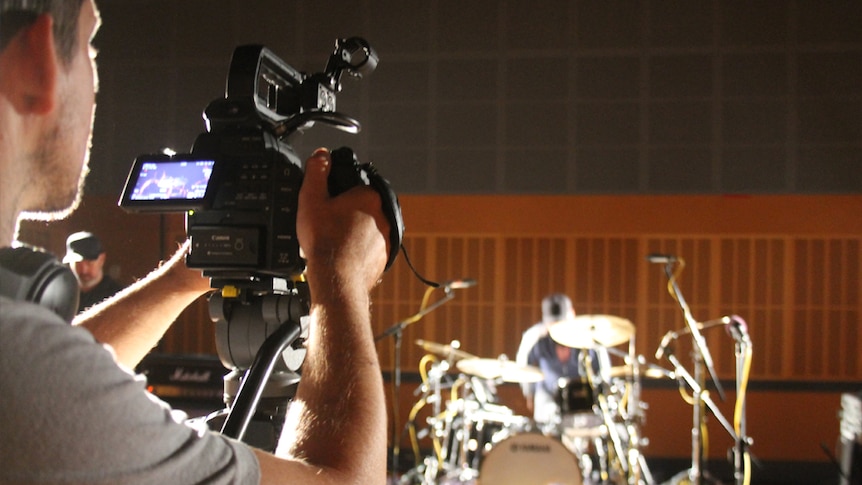 A producer films a drummer.