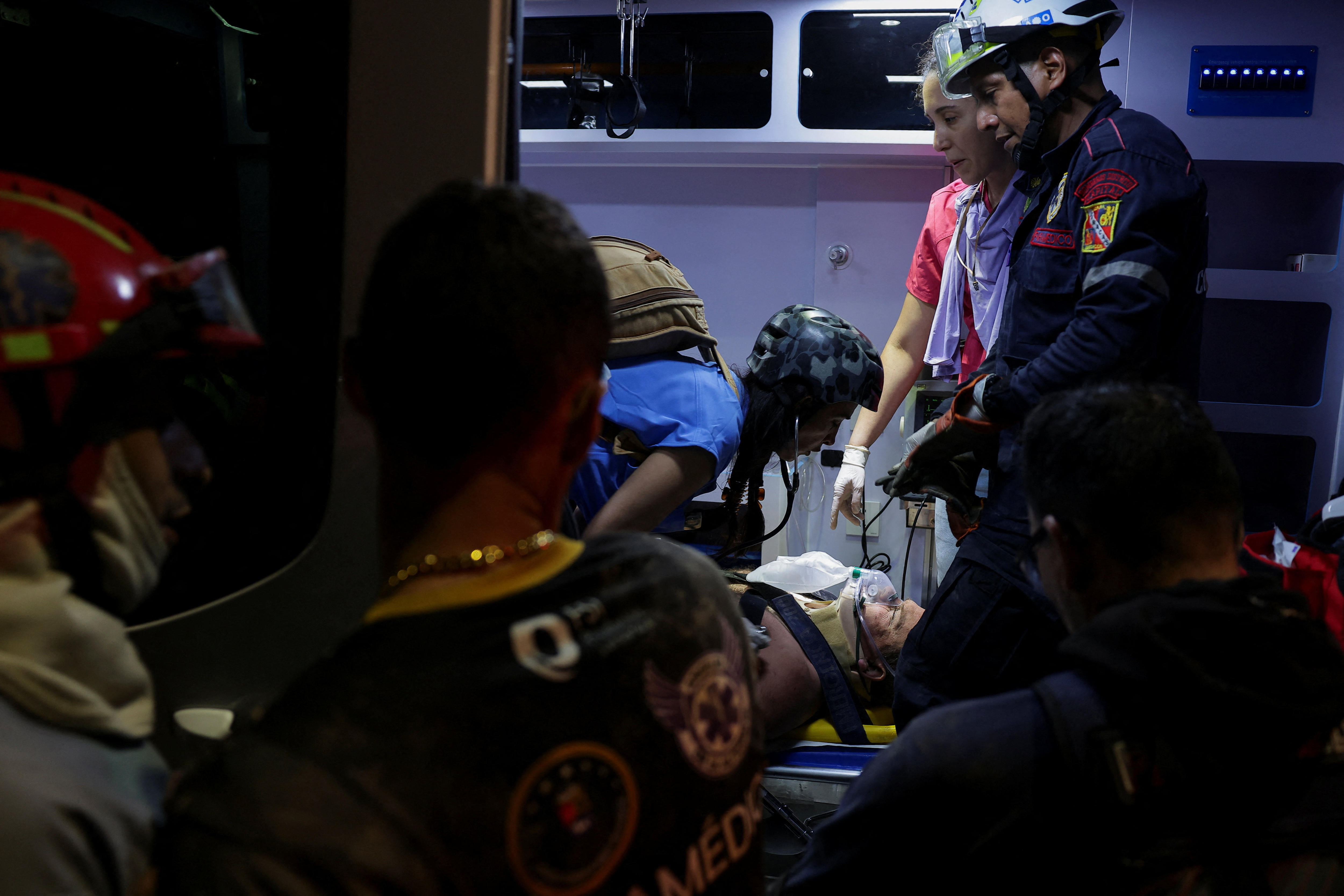 people in the back of an ambulance work on an injured person 