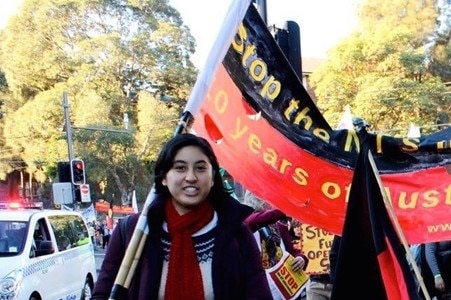 Bridget Harilaou holds up a flag at what looks like a protest.