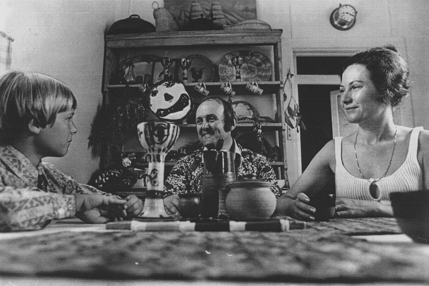 A black and white photograph of a man and woman with their son sitting at dinner table