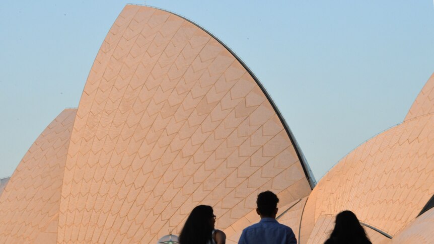 the outside of the opera house sails as people walk past