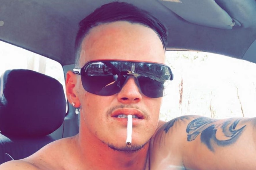Andrew Julian Stewart-Smith wears sunglasses while a cigarette sticks out of his mouth